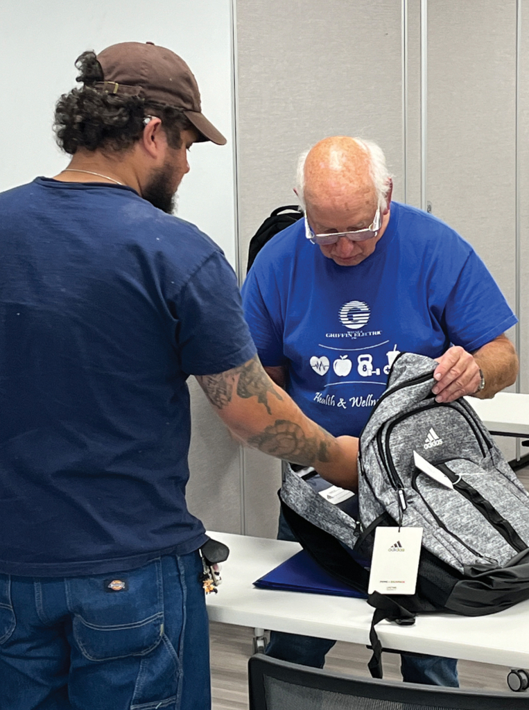 Two men examining a backpack in an indoor setting.