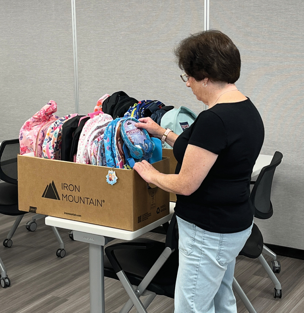 A woman sorting colorful fabric items from a box on a table.